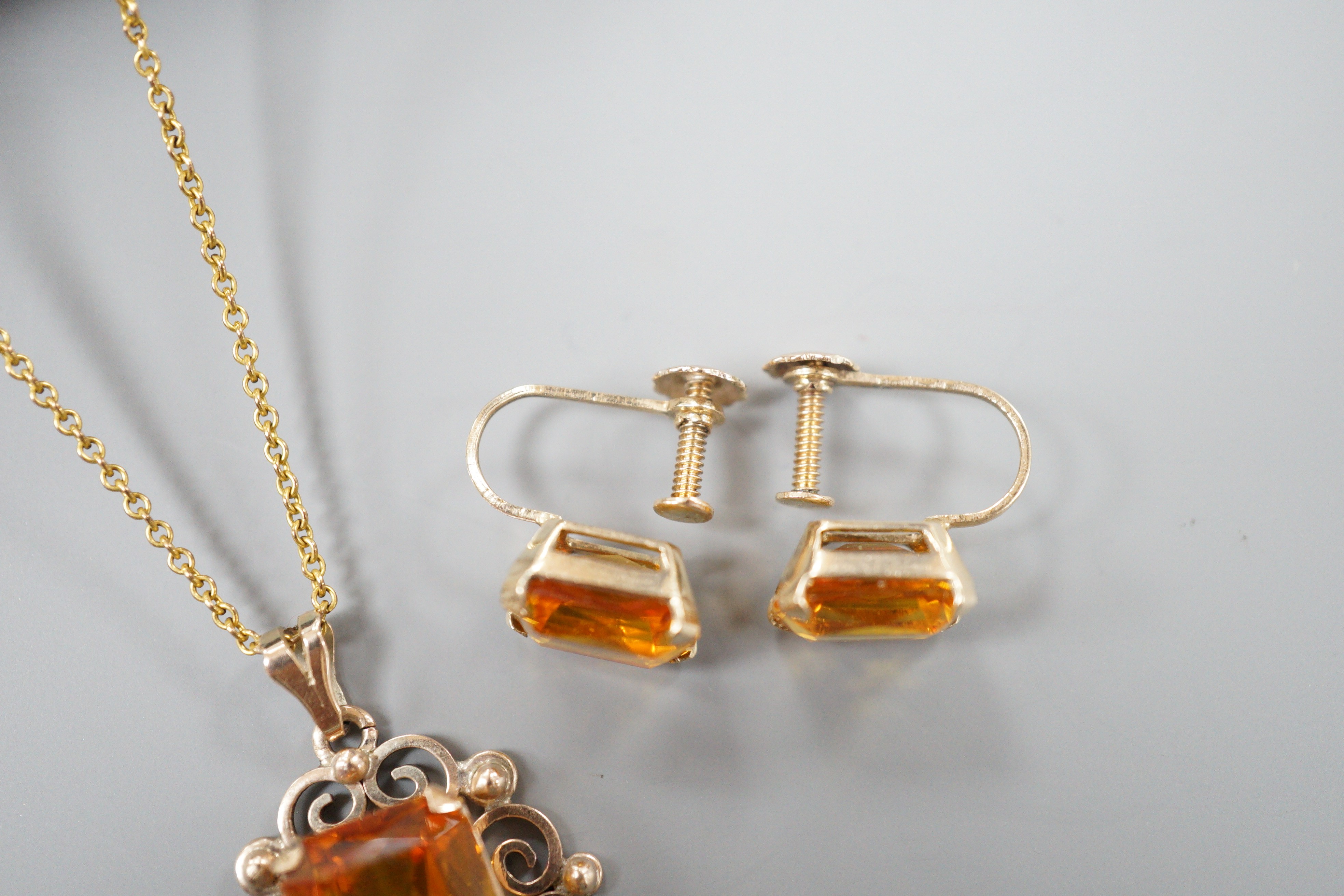 A yellow metal and citrine set pendant, 29mm, on a gold plated chain and a pair of 9ct and citrine set ear clips, gross 8.2 grams.